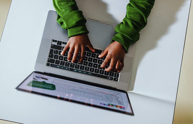child typing on laptop